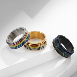 Detalle de anillos giratorios plateados, dorados y negros con rayas esmaltadas arcoíris