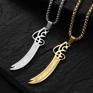 Macro shot of 18K gold and silver Zulfiqar knife pendants with Arabic engraving