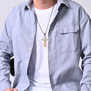 Men's titanium steel cross pendant necklace with shell texture on light blue shirt