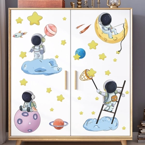 Detail showing cartoon astronaut wall stickers on a white wooden wardrobe in a kids' room