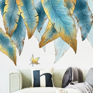 Macro detail of tropical blue and gold leaf wall decals above a green sofa in a modern room