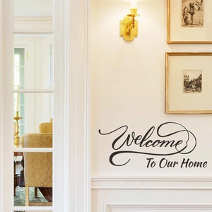 Welcome To Our Home black wall decal in a modern entryway with elegant wall lamp