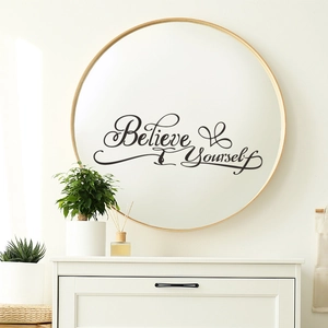 Détail macro du sticker noir 'Believe Yourself' appliqué sur la surface d'un miroir rond