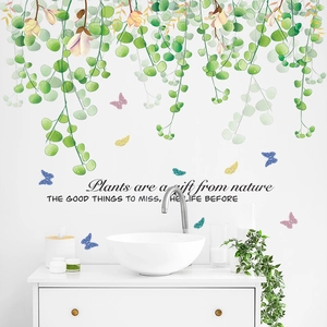 Close-up of green plant wall stickers with butterflies and nature quote on white wall