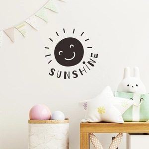 Close-up of black smiling sun wall sticker and sunshine text in a Nordic nursery setting