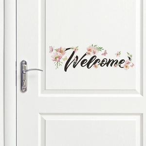 Sticker mural Welcome autocollant avec lettrage noir, fleurs roses et papillons décoratifs