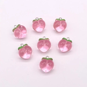 Detailed close-up of seven pink resin peach charms with green leaves and metal rings