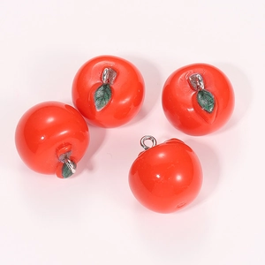 Detail of four glossy red resin apple pendants with green leaves and metal rings