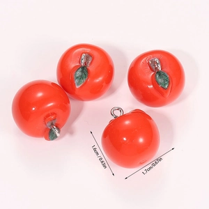 Close-up of four red resin apple pendants with silver metal rings and green leaves