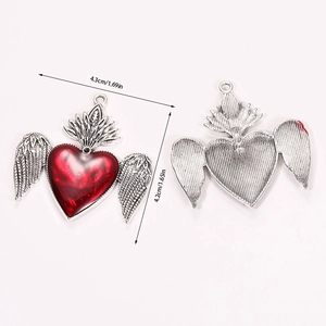 Detailed view of gothic winged heart pendant in silver alloy with red enamel center
