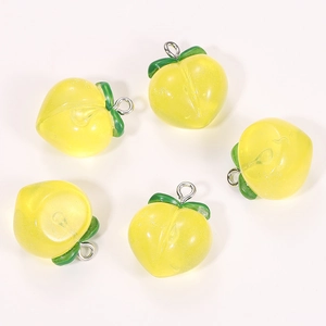 Close-up of five yellow resin peach pendants with glitter effect and green leaves