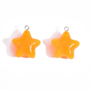 Close-up of bright orange jelly acrylic star pendants with silver metal rings for DIY