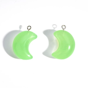 Detail of translucent green acrylic moon pendants with silver rings for jewelry DIY