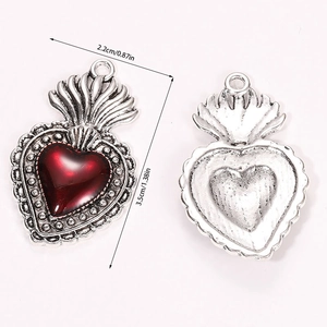 Macro detail of gothic sacred heart pendant showing red oil drip and vintage silver finish