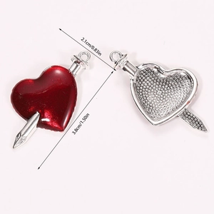 Detailed view of silver heart pendant with red enamel and spike, sizing 2.1cm by 3.8cm