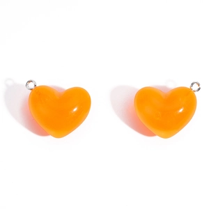 Deux pendentifs cœur en acrylique orange vif avec anneaux métalliques sur fond blanc