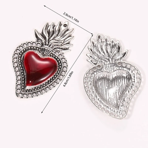 Detail showing front and back of vintage silver sacred heart pendants with red enamel
