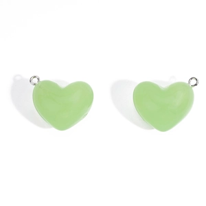 Vue détaillée de deux pendentifs cœur en acrylique vert clair avec anneaux en métal
