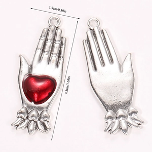 Detailed view of silver gothic hand charms with red heart inlay and size annotations