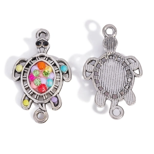 Macro detail of antique silver turtle pendant with colorful resin beads and rhinestones