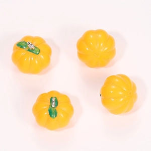 Detailed view of four yellow resin pumpkin charms with green stems for DIY jewelry making