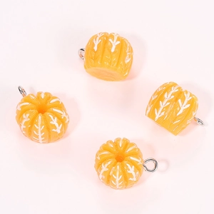 Detail of four resin pumpkin charms with white textures and silver jump rings for DIY crafts
