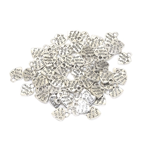 Gros plan de breloques en cœur argenté gravées Made with Love pour bijoux artisanaux