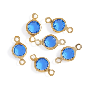 Detailed macro view of faceted blue glass connectors with golden brass borders for DIY jewelry
