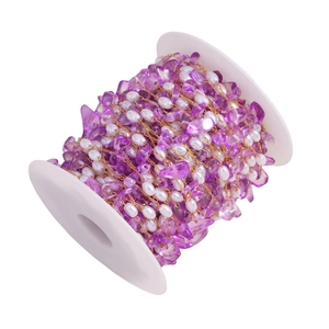 Detailed macro of purple stone and white pearl bead chain wrapped on a spool