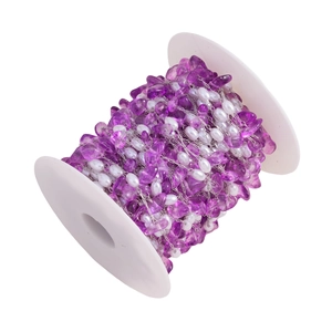 Macro shot of purple gravel stones and white pearls on a stainless steel DIY jewelry chain