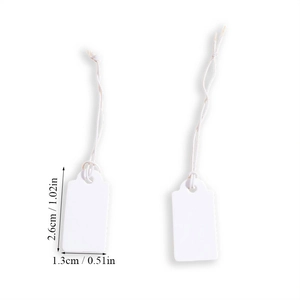 Close-up of small white paper gift tags with cotton strings measuring 2.6cm by 1.3cm