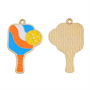 Detail of pickleball paddle charms showing colorful enamel inlay and golden textured back