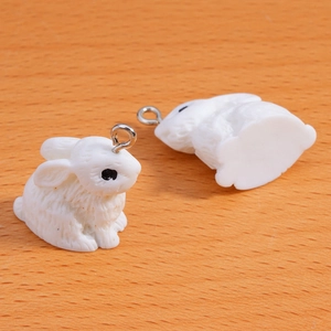 Close-up of white flocked rabbit charms with fine fur texture and silver metal rings