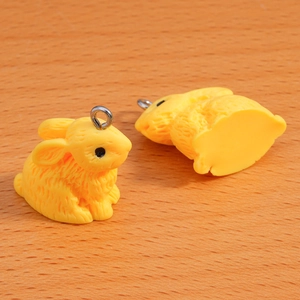 Macro view of bright yellow resin flocked bunny charms with silver metal rings for DIY crafts