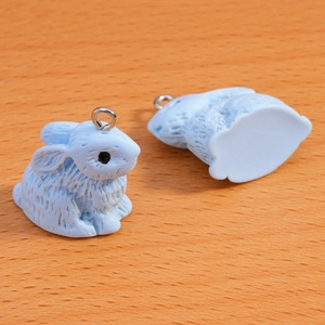 Detailed view of light blue flocked bunny pendants with fuzzy texture and silver metal loops