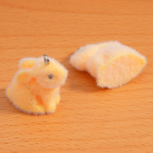 Close-up of fluffy flocked rabbit pendant with metal ring on natural wood surface