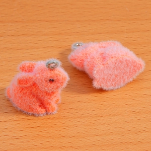 Close-up of bright orange flocked rabbit charms with silver metal rings for DIY jewelry
