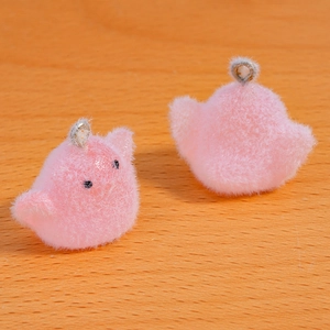 Close-up of two pink flocked bird charms with silver metal rings on wooden surface