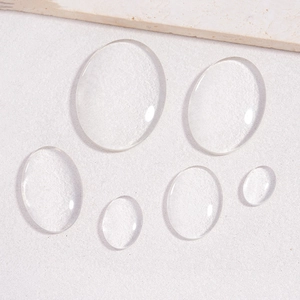Oval transparent glass cabochons for DIY jewelry making on a light textured stone background