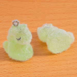 Détail macro de pendentifs dinosaures floqués vert clair avec anneaux en métal argenté