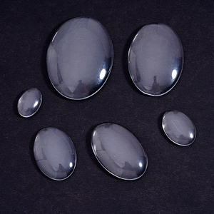 Clear oval glass cabochons for DIY jewelry making in multiple sizes on black background