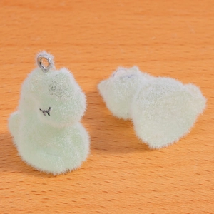 Gros plan de deux pendentifs dinosaures floqués vert clair avec texture douce et anneaux