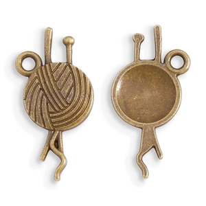 Detailed macro view of vintage bronze alloy yarn ball and needle charms for DIY jewelry
