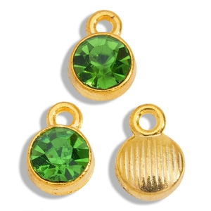 Macro shot of gold-plated birthstone pendants with green faceted crystals and textured back
