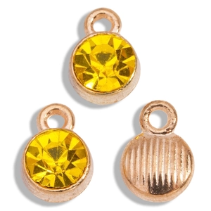 Detail of three rose gold birthstone charms with faceted yellow crystals and textured back