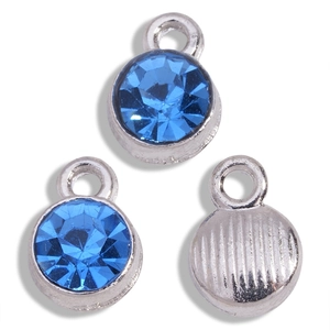 Macro shot of silver alloy pendants with round sapphire blue rhinestones and textured back