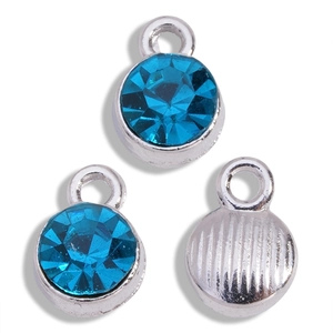 Detail of round light blue rhinestone pendants with polished silver alloy base and back texture