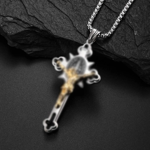 Detailansicht eines silbernen Kreuzanhängers mit goldener Jesusfigur auf dunklem Stein