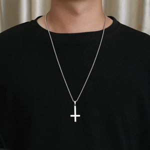 Nahaufnahme eines silbernen Petruskreuz-Anhängers an einer Stahlkette auf schwarzem Shirt