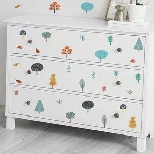 Detailed view of colorful cartoon tree wall stickers applied to a white dresser and wall